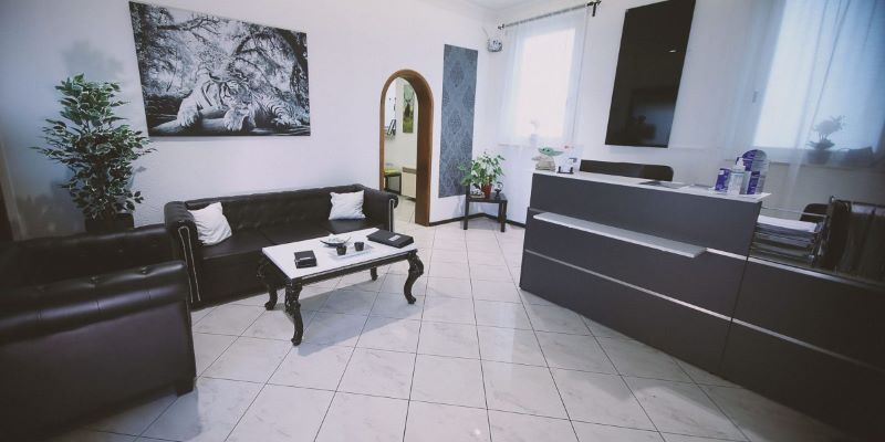 Eingangsbereich eines Tattoo Studios mit einem modernen Empfangstresen und gemütlicher Lounge-Einrichtung.
