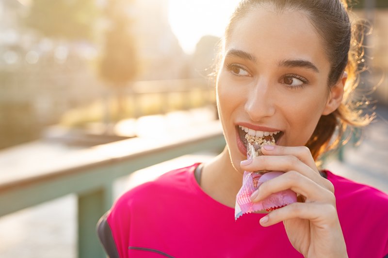 Sportliche Frau isst einen Proteinriegel