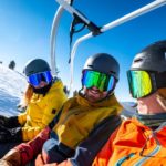 Skifahrer tragen Skibrillen und sitzen im Skilift.
