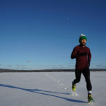 Mann mit Laufhandschuhen laeuft im Schnee