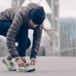 Frau bindet sich nach dem Laufen gehen die Schuhe im Winter.