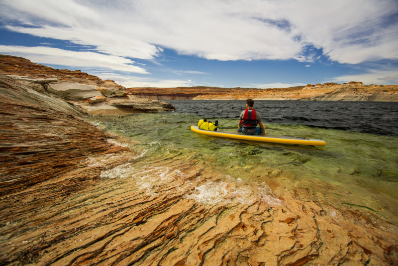 Mann mit Schwimmweste auf SUP-Board
