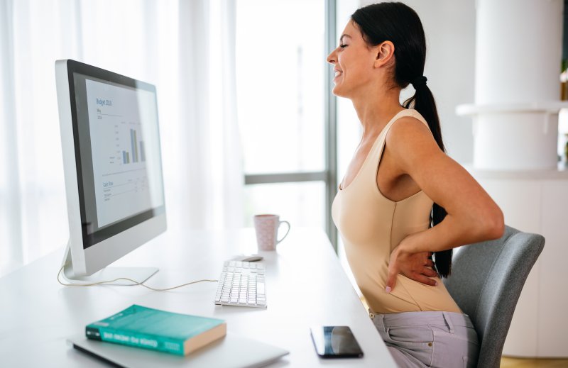 Frau hat Rückenschmerzen vor dem Computer