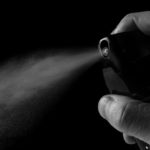 Eine Hand betätigt ein Pfefferspray, das einen Sprühstoß abgibt