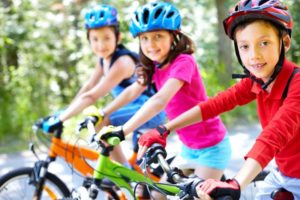 drei Kinder auf Kinderfahrrad sitzend mit Helm