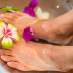 Frau nimmt Fußbad mit Blumen im Wasser