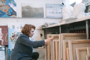 Eine Frau durchsucht mehrere Malerleinwände.