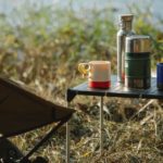 Thermoskannen auf einem Tisch beim Campen am See