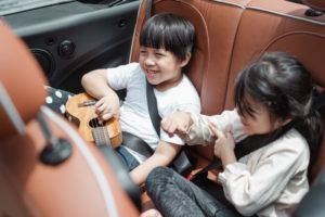 Kinder sitzen hinten in einem Auto und haben Spaß.