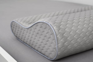 Ein graues orthopädisches Nackenkissen in Wellenform