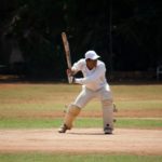 Mann spielt Cricket und hält einen Schläger in der Hand.