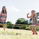 Kinder springen draußen Gummitwist