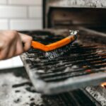 Grill wird mit einer Drahtbürste gereinigt