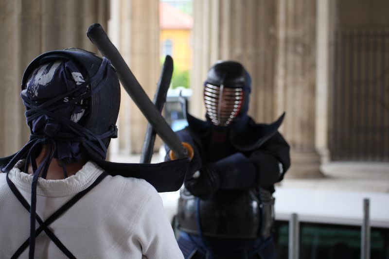 Zwei Männer in traditioneller Kampfkunstkleidung üben zusammen im Dojo.