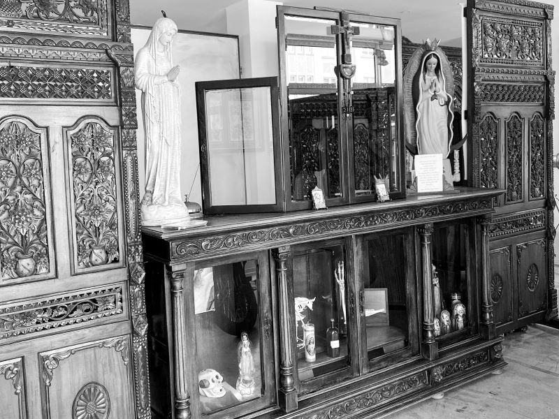 Innenansicht eines Tattoo-Studios mit kunstvollen Holzmöbeln und religiösen Figuren, die eine einzigartige Atmosphäre schaffen.