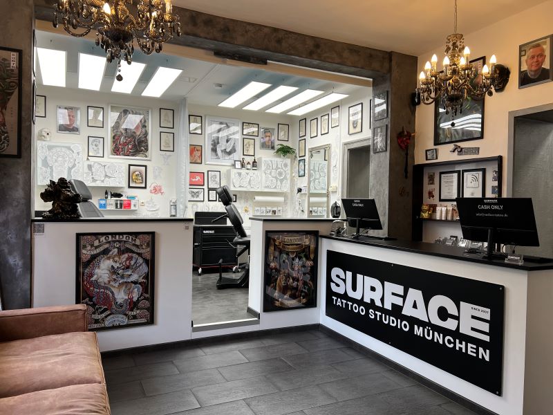 Innenansicht des Empfangsbereichs eines Tattoo-Studios, mit vielen Bildern an den Wänden und einer gemütlichen Atmosphäre.