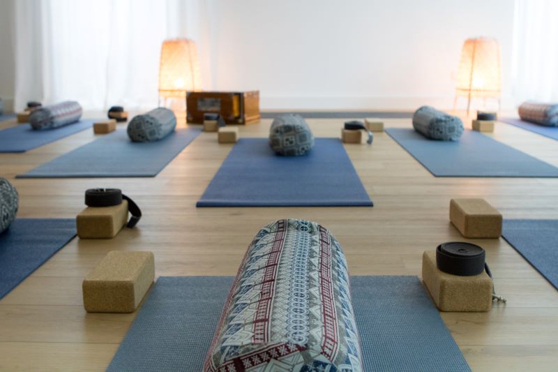 in Yoga-Raum mit Matten, Yogaklötzen, Bolstern und sanfter Beleuchtung, bereit für eine Yogastunde.