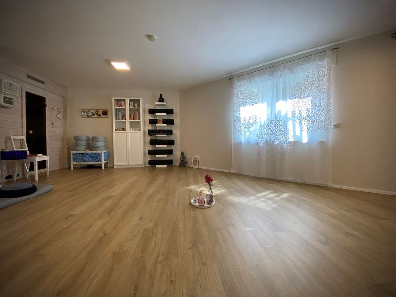 Ein gemütlicher Yogaraum mit Holzfußboden, sanfter Beleuchtung und entspannter Atmosphäre.