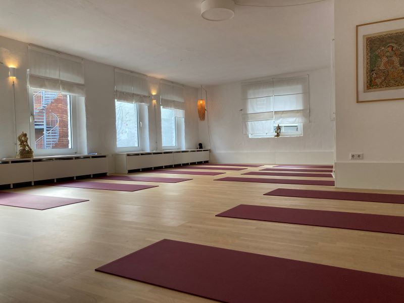 Ein heller Yogaraum mit mehreren Yogamatten, bereit für eine Unterrichtsstunde.
